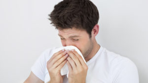 Man Sneezing Into A Tissue